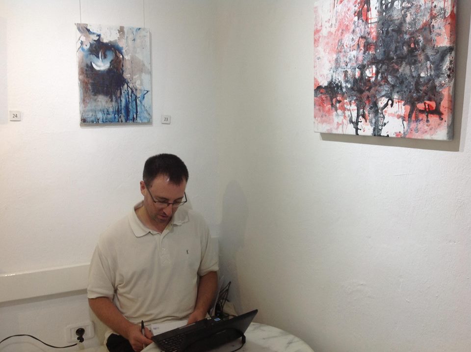 Jean-Baptiste Mesona écrivant devant des tableaux de Rim Ayari en 2015