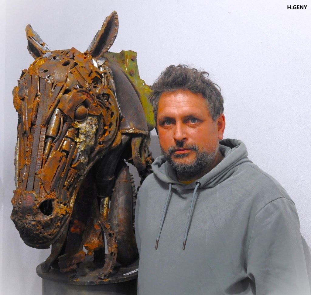Romain Bresson auprès de sa sculpture de cheval en métal de récupération, buste grandeur nature à la patine rouillée